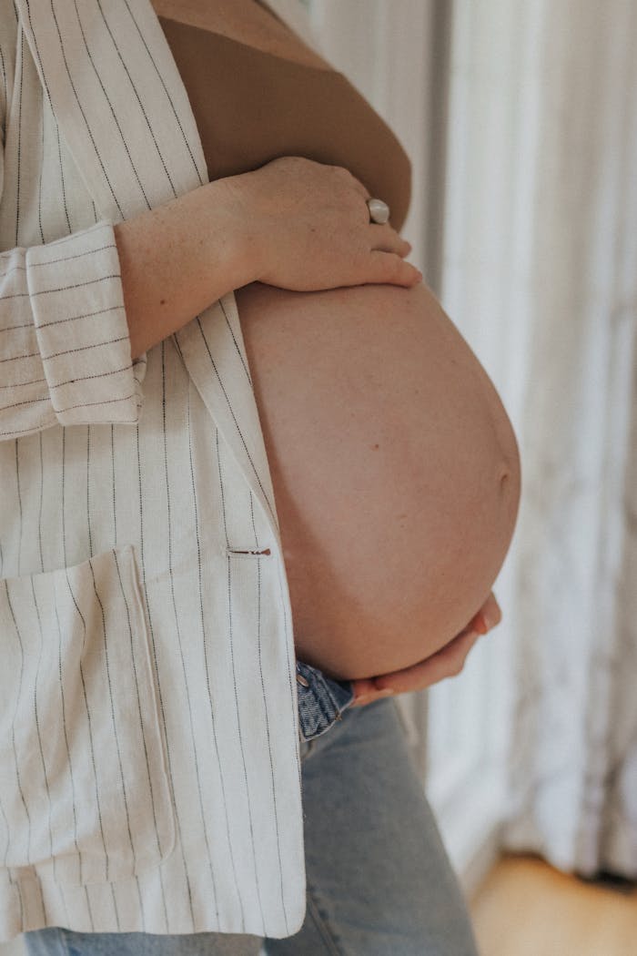 A tranquil moment capturing a pregnant woman gently holding her belly indoors.